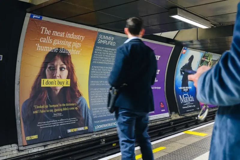 A large End Factory Farming campaign poster featuring comedian Diane Morgan and the text "I don't buy it." on a London Underground platform, with commuters walking past.