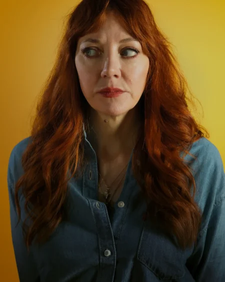 Comedian Diane Morgan against a yellow background, with a sceptical expression on her face.